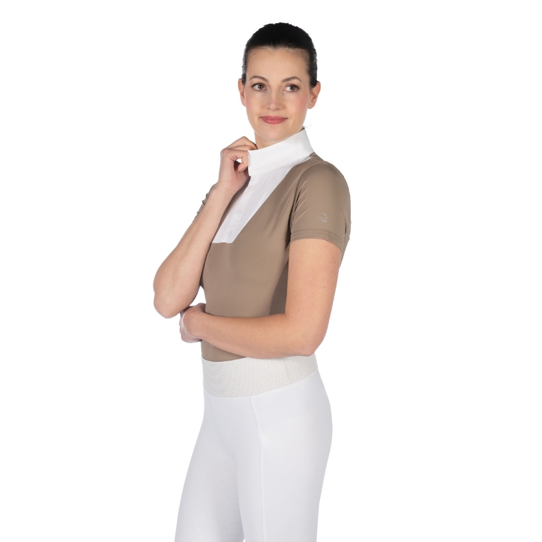 Woman in a beige short-sleeve top and white high-waisted pants, adjusting a white collar, posing sideways in profile view.