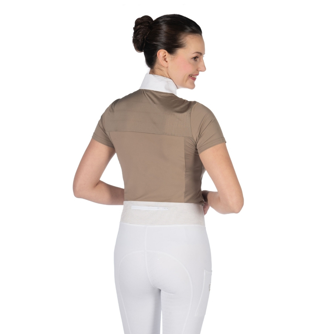 Back view of a woman wearing a beige short-sleeve top, white riding pants, and a wide white back-support belt around her waist.