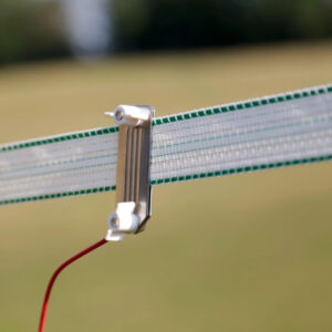Close-up of a white plastic clamp gripping a metal strip on a mesh net, with a red wire connected to it
