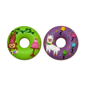 Two colorful donut-shaped decorations: green side with a monkey, party hat and cake; purple side with a white alpaca and balloons.