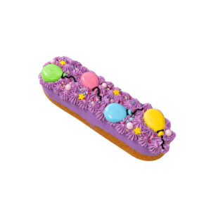 Colorful éclair with purple icing, star sprinkles, and balloon-shaped candy decorations in green, pink, blue, and yellow.